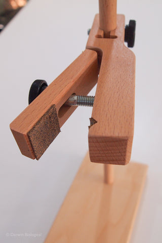 Close-up of a wooden adjustable single retort stand or clamp with a threaded screw, black knobs, and a light wood base on a white background.